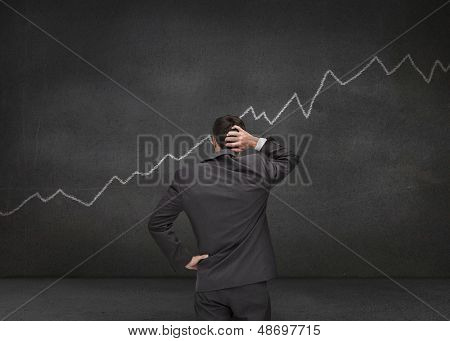 Empresário hesitando olhando branco gráfico desenhado em um quadro negro