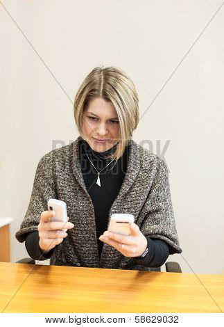 Busy Caucasian Woman Trying To Respond To Two Phone Calls