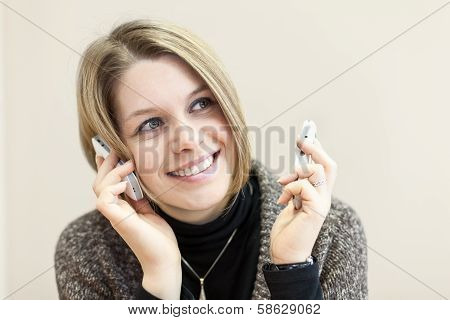 Portrait Of Young Woman With Two Cellphones In Hands