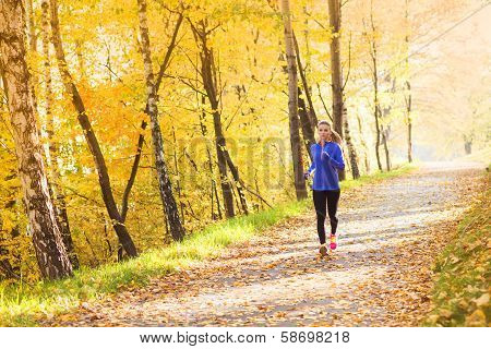 Active and sporty woman runner in autumn nature