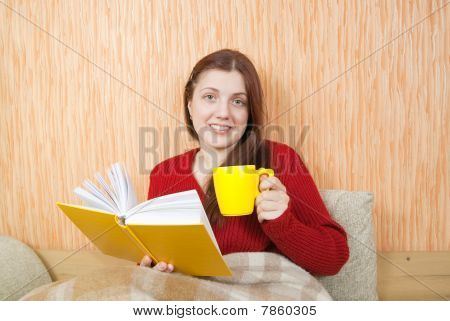 Pretty Young Girl Reading Book On Sofa