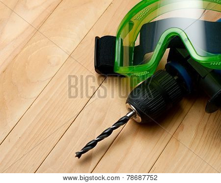 Handdrill And Goggles On Wooden Background