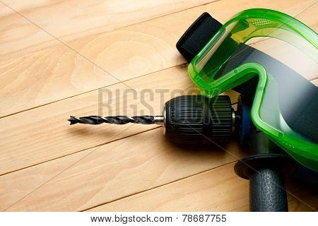 Handdrill And Goggles On Wooden Background