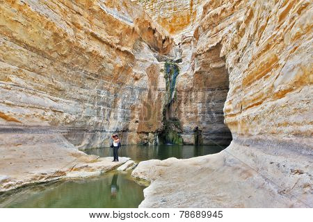 Beautiful gorge in the Negev desert. Ein Avdat Canyon, a female photographer taking pictures scenic landscape