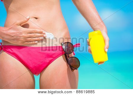 Woman hand putting sunscreen from a suncream bottle
