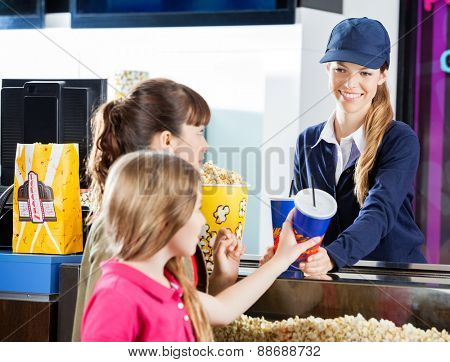 Sisters buying snacks from female concession worker at cinema counter