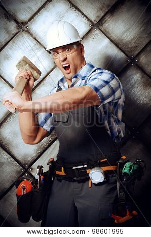 Expressive costruction worker wearing uniform and tools over grunge industrial background. Job, occupation. 