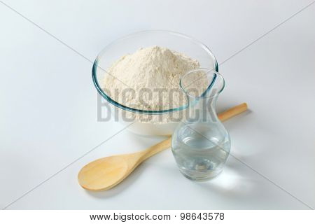 white wheat flour in a glass bowl and a carafe of cold water