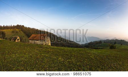 Autumn sunset at hillsides and meadow with mist over Danube river
