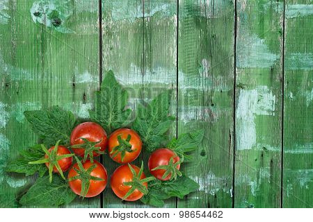 Fresh red tomatoes with leaves on wooden background