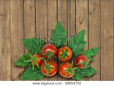 Fresh red tomatoes with leaves on wooden background