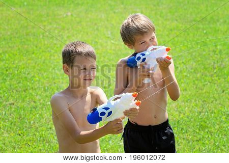 Kids playing with water guns at hot summer day