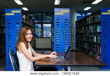 Young Girl using Laptop Computer on Table in Library Room
