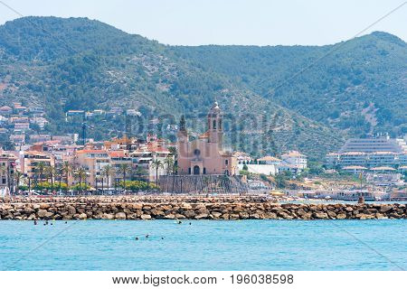 Stony Beach And Church Of Sant Bartomeu And Santa Tecla In Sitges, Barcelona, Catalunya, Spain. Copy