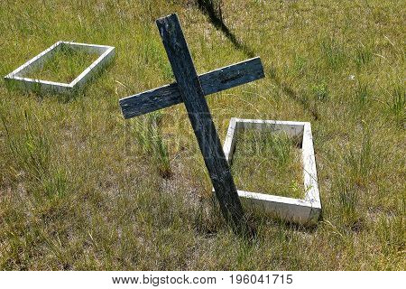 Leaning cross and two old wooden boxes indicate the graveside of children buried in a remote prairie cemetery