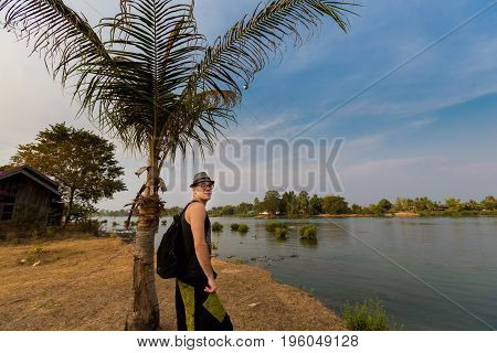 Young male tourist walking across Don Det island in south Laos. Landscape of nature on four thousands islands Si Phan Don on Mekhong river in south east asia during summer.