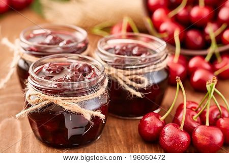 Cherry jam on wooden ground with fresh cherries