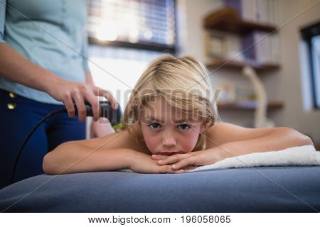 Portrait of boy lying on bed with female therapist using ultrasound scan at hospital ward