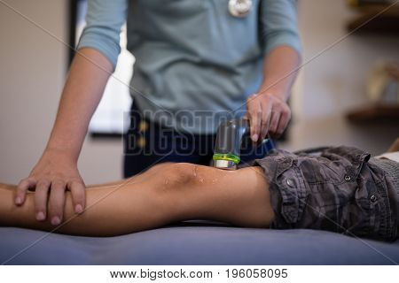 Midsection of boy receiving ultrasound scan from female therapist at hospital ward