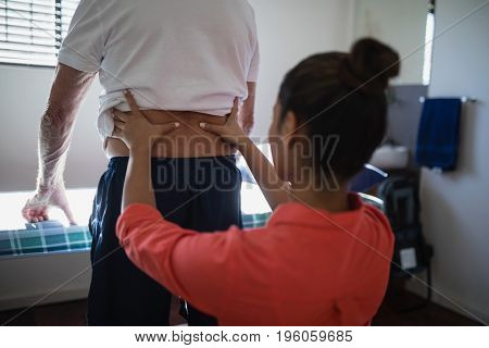 Rear view of female therapist massaging back at hospital ward