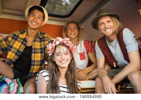 Low angle portrait of smiling young friends sitting together in camper van