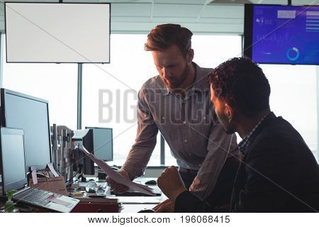 Male business colleagues working together at desk in office