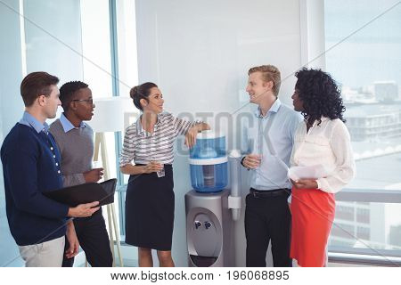 Young coworkers discussing while standing at office