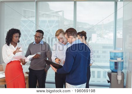 Young business colleagues discussing while standing in office