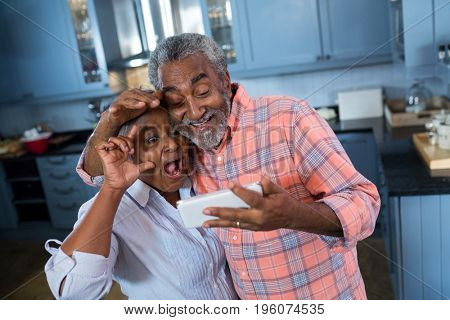 High angle view of senior couple taking selfie while standing in kitchen at home