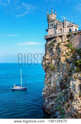GASPRA CRIMEA - July 07 2011: The famous castle 'Swallow's Nest' or 'Lastochkino Gnezdo' on a rock and a passing yacht on a clear sunny day. Sight of the southern Crimean coast. The suburb of Yalta.