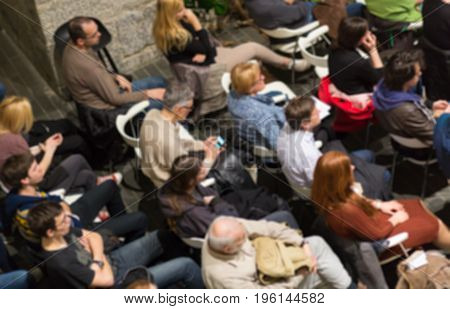 Abowe shot of blured audience in conference hall. Presentation in lecture hall at university workshop. Rear view of unrecognized participant in audience. Scientific conference event.