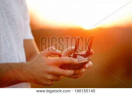 Man holds a drone remote controller in his hands. Close-up of quadcopter RC with antennas during flight. Pilot takes aerial photos and videos with quad