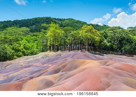 Chamarel Mauritius - December 26 2015: People watching for main sight of Mauritius - Seven Coloured Earth in Mauritius Chamarel nature reserve. Green forest behind and blue cloudy sky.