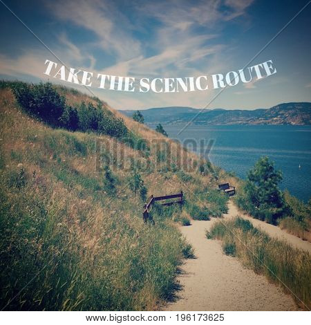 Motivational text in white font on scenic lake and mountains landscape from hilltop with grass. Trails on hillside and along shoreline with parasol on beach.