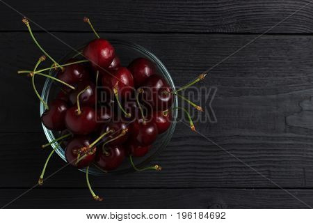 Cherry In A Glass Plate Top View On A Black Wooden Background