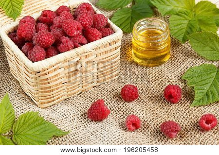 Fresh raspberries in a wicker box and honey green leaves.