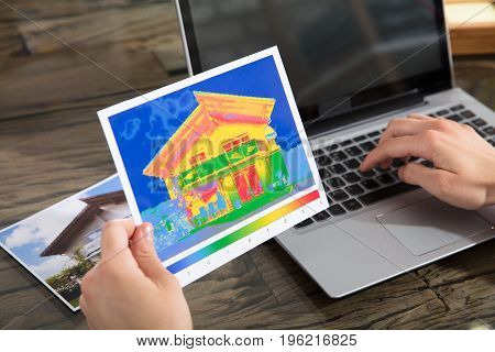 Close-up Of A Person Detecting Heat Loss Of A House Using Laptop On Desk