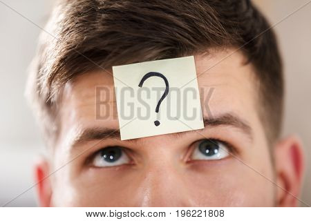 Close-up Of A Businessperson's Forehead With Question Mark On Sticky Note