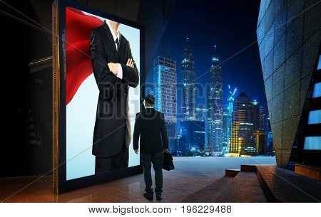 Young businessman looking the hero businessman on the advertising billboard screen . Successful businessman concept .
