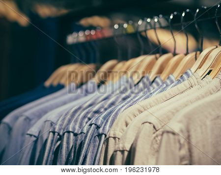 Close up view of man clothes hang in clothes store. Hangers with different male clothes. Copy space. Selective focus. Toned image