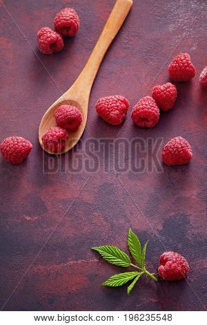 Raspberries with spoon. A fresh raspberry on a wooden spoon. Ripe fresh raspberries with leaves on rustic background.