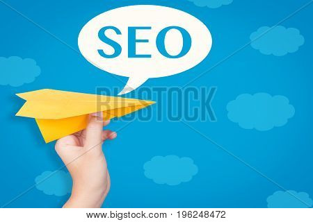 hand holding paper plane with seo in speech bubble on blue background illustration
