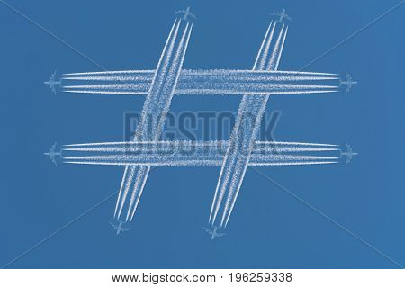 Four airplanes leave contrails in the form of the special sign # Hashtag against a dark blue sky.