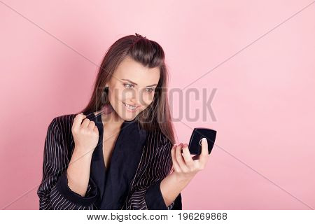 girl in coat makes brush makeup looks in the mirror 1