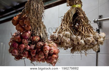 Shallots and garlics hang in kitchen room