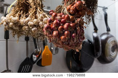 Shallots and garlics hang in kitchen room