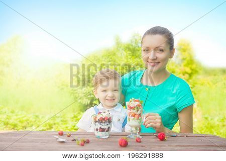 Happy Loving Family. Mother And Her Son Child Boy Are Eating Laered Dessert In Sunny Day In Green Ga