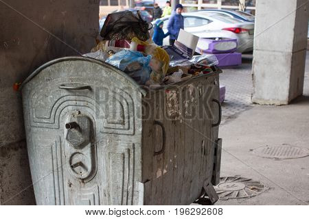 Full trash can with unsorted garbage. Throw out. Metal container.