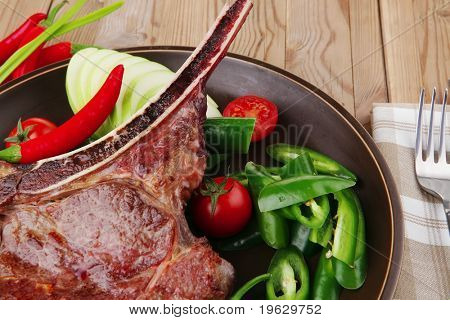 cibo di carne: manzo alla griglia di ricambio rib sul piatto scuro con pepe timo e pomodoro sul tavolo di legno