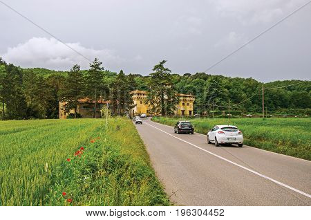Emilia-Romagna, Italy - May 12, 2013. Overview of fields with wheat, road with cars and castle in the middle of the forest. Located in the Emilia-Romagna region, northern Italy